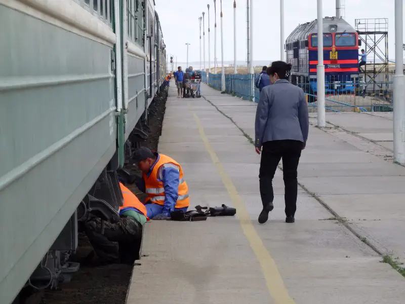 Maintenance staff carrying out repair works on a Tran-Siberian/ Trans-Mongolain train at a stop.